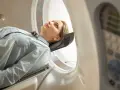 Kobieta leży w aparacie do tomografii głowy, przygotowując się do badania.