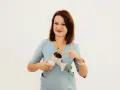 Kobieta w niebieskiej bluzce wskazuje palcem na różowy laktator elektryczny.
