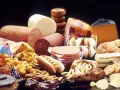 Stół ugina się pod ciężarem przetworzonej żywności: wędliny, sery, frytki, słodycze, ciastka, pączki, hamburgery i chipsy – to wszystko zawiera tłuszcze trans.