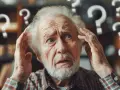 Starszy mężczyzna zdezorientowany, trzymający się za głowę. Wokół niego unoszą się znaki zapytania, symbolizujące chorobę Alzheimera i utratę pamięci.