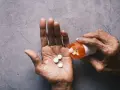 Dłoń wysypuje tabletki Tylenol z pomarańczowej buteleczki.
