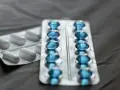 Dwa blistry leków: jeden z białymi kapsułkami, drugi z niebieskimi, które mogą być pregabalin sandoz.