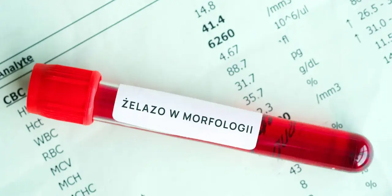 Probówka z krwią na tle wyników badań laboratoryjnych z napisem "Żelazo w morfologii".