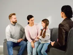 Rodzina z córką siedzi na kanapie podczas sesji z psychologiem.