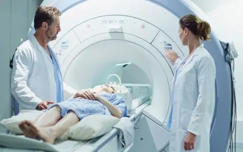Pacjentka leży w skanerze MRI, podczas gdy lekarze przygotowują badanie. To właśnie mri co to za badanie, które pozwala zajrzeć do wnętrza ciała.