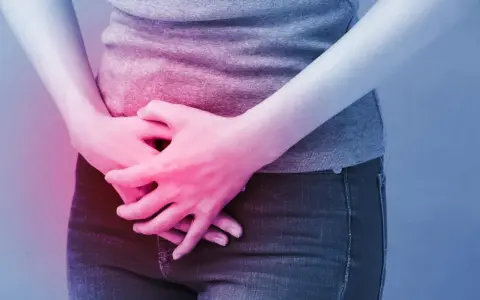 Osoba trzyma się za brzuch, odczuwając ból. Może to być objaw problemów, w leczeniu których pomaga Ditropan.