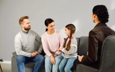 Rodzina z córką siedzi na kanapie podczas sesji z psychologiem.