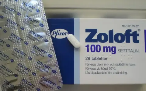 Opakowanie leku Zoloft 100 mg z sertraliną i pojedyncza tabletka. Lek ten pomaga w leczeniu depresji.