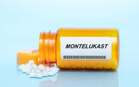 Pomarańczowa butelka leku Montelukast z białymi tabletkami na jasnoniebieskim tle.