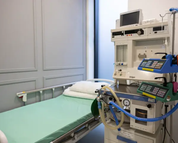 Łóżko szpitalne i aparat do znieczulenia ogólnego.