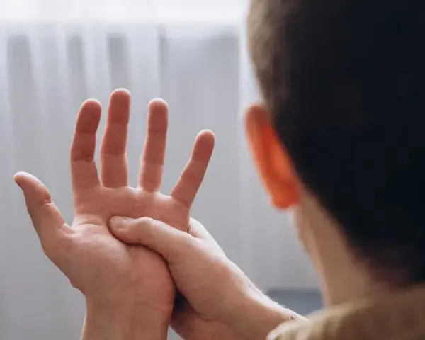 Mężczyzna masuje dłoń, odczuwając drętwienie rąk.
