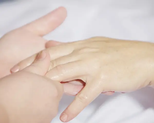 Delikatny masaż dłoni, łagodzący objawy **cieśni nadgarstka**. Dłonie są nawilżone, a palce rozluźnione.