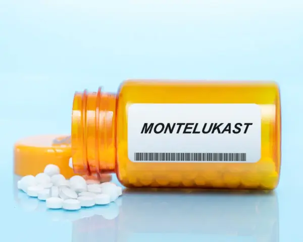 Pomarańczowa butelka leku Montelukast z białymi tabletkami na jasnoniebieskim tle.