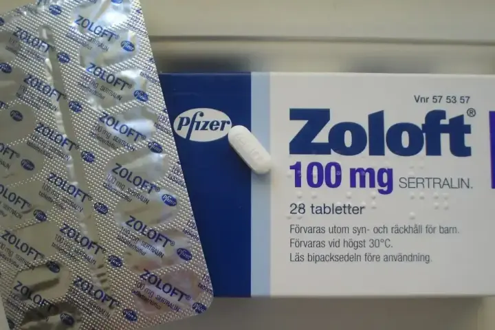 Opakowanie leku Zoloft 100 mg z sertraliną i pojedyncza tabletka. Lek ten pomaga w leczeniu depresji.