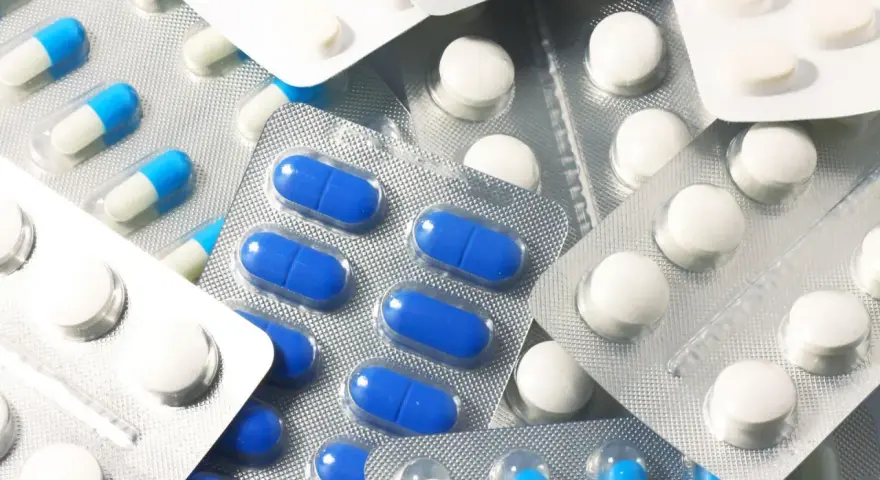 Blistry z białymi i niebiesko-białymi kapsułkami oraz białe tabletki. Wśród nich można znaleźć polopirynę, która pomaga złagodzić ból i gorączkę.