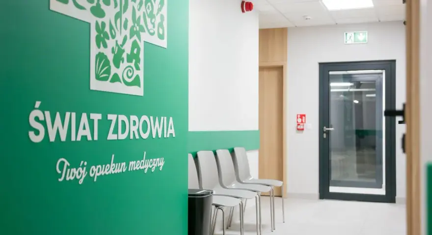 Nowoczesna poczekalnia kliniki medycznej z zieloną ścianą i napisem "Świat Zdrowia".