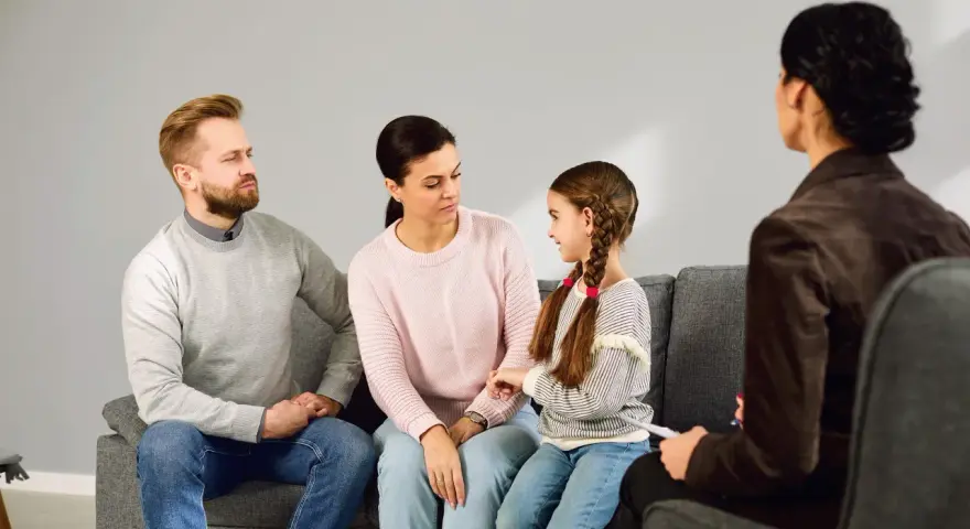 Rodzina z córką siedzi na kanapie podczas sesji z psychologiem.