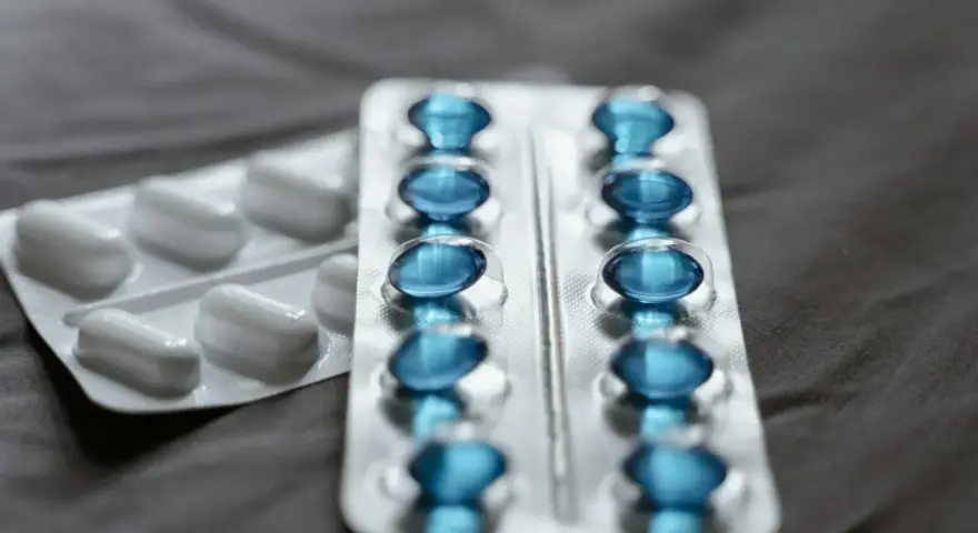 Dwa blistry leków: jeden z białymi kapsułkami, drugi z niebieskimi, które mogą być pregabalin sandoz.
