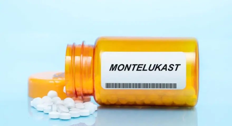 Pomarańczowa butelka leku Montelukast z białymi tabletkami na jasnoniebieskim tle.