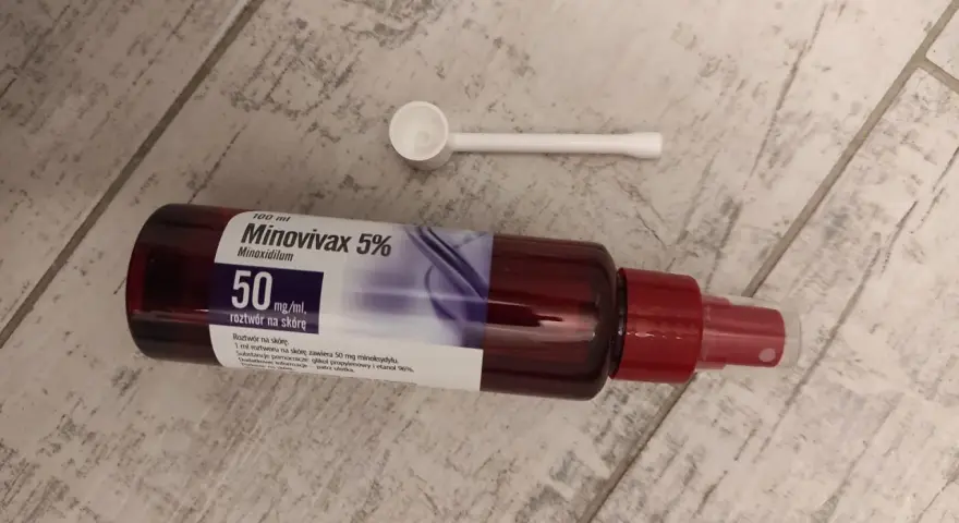 Butelka Minovivax 5% z aplikatorem na drewnianym tle.