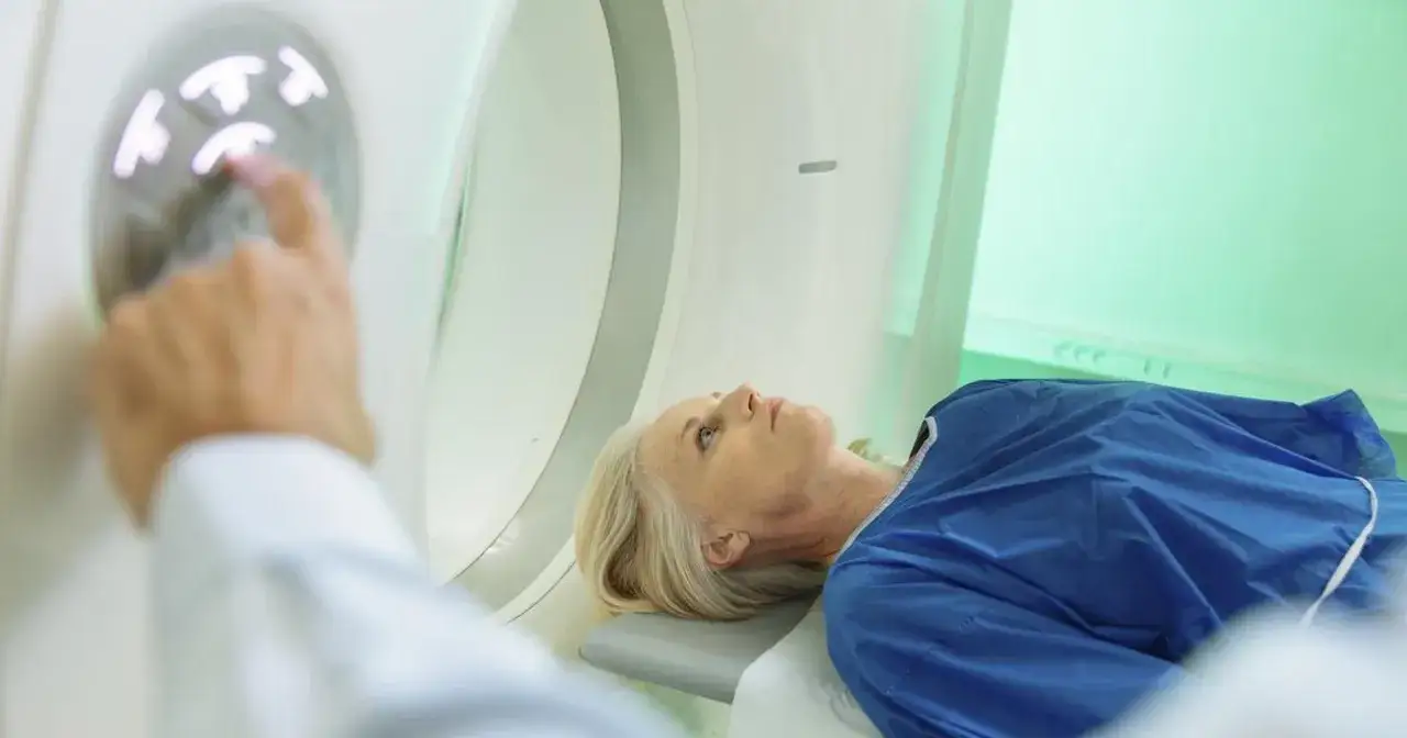 Pacjentka leży podczas tomografii głowy, a technik uruchamia badanie.