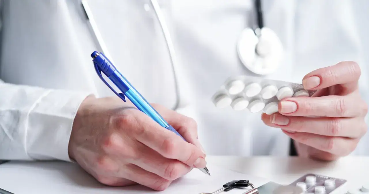 Lekarz przepisuje receptę na alprazolam, trzymając w dłoni opakowanie tabletek.