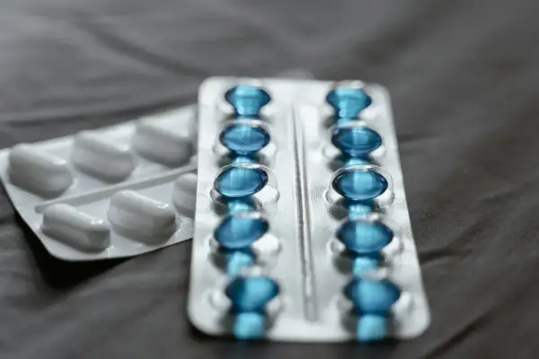 Dwa blistry leków: jeden z białymi kapsułkami, drugi z niebieskimi, które mogą być pregabalin sandoz.